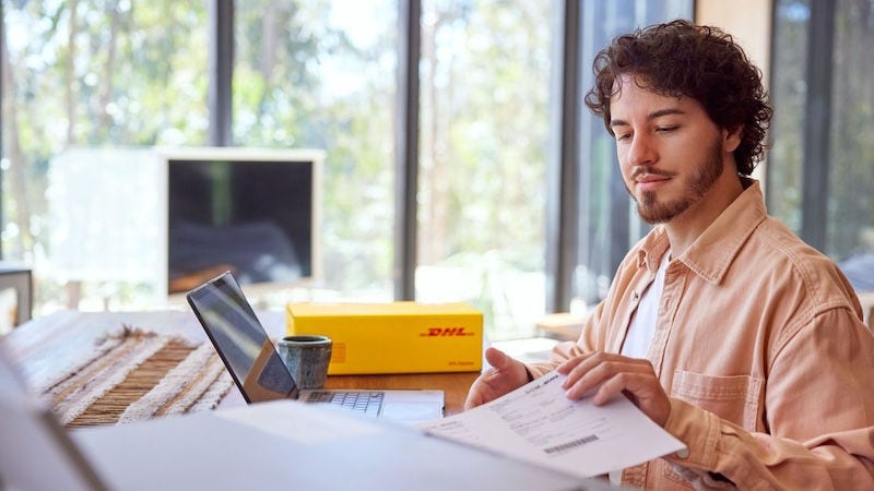 Man working from laptop with DHL package in background