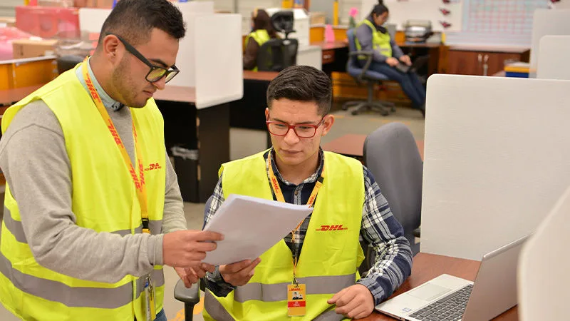two DHL employees looking a a sheet of paper