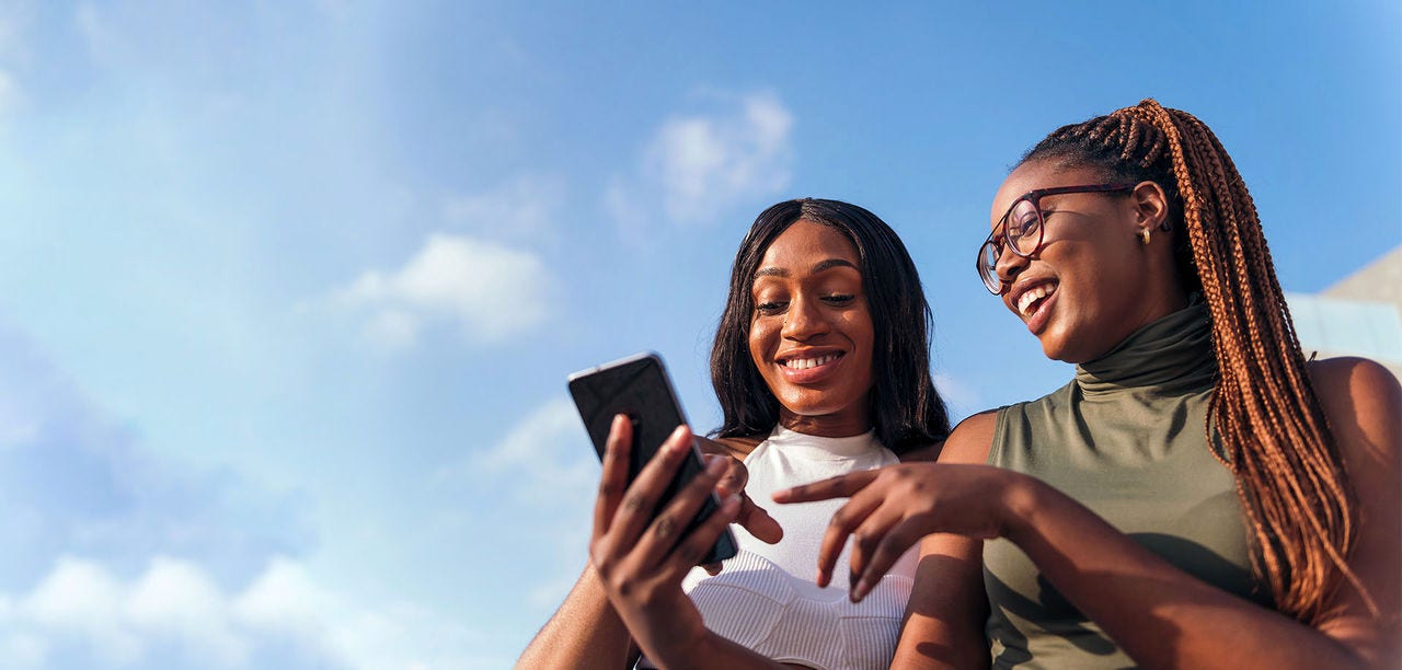 two women smiling at mobile phone screen