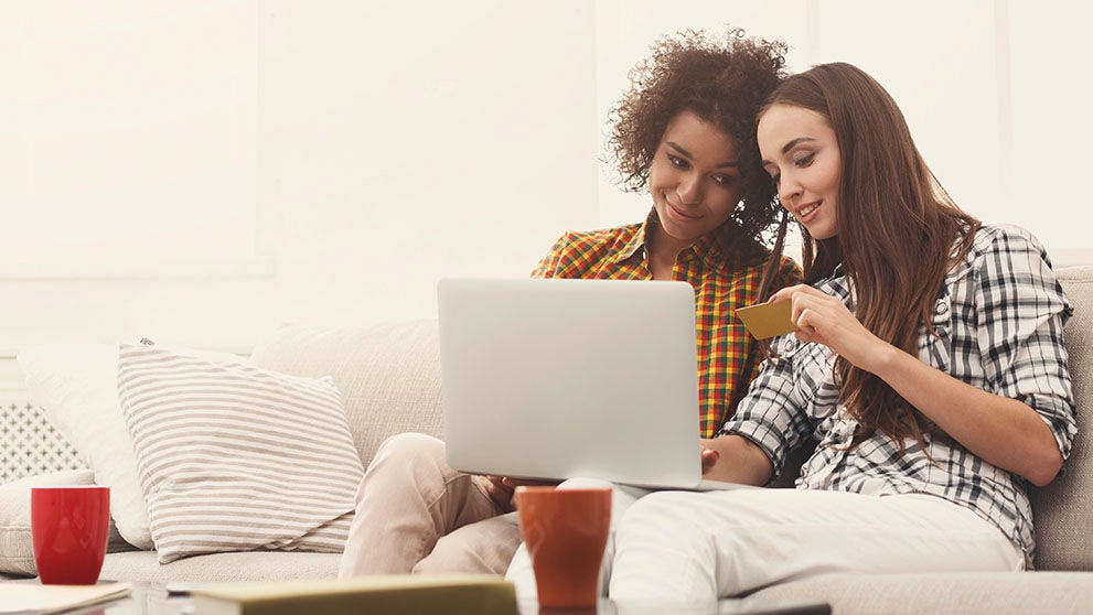 two women smiling and looking at credit card