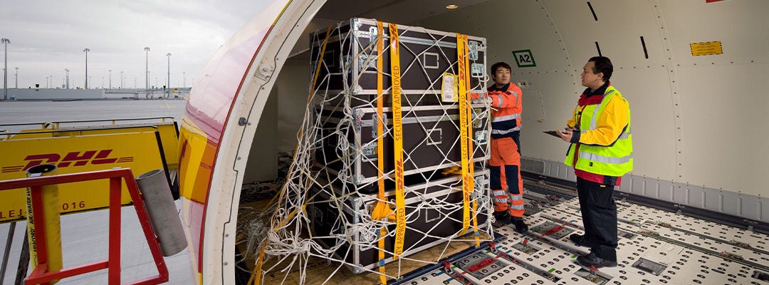 DHL workers pushing a pallet with trunks