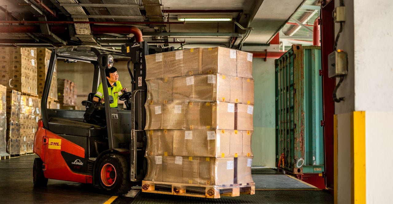 dhl express employee moving a pallet with heavy goods with a forklift