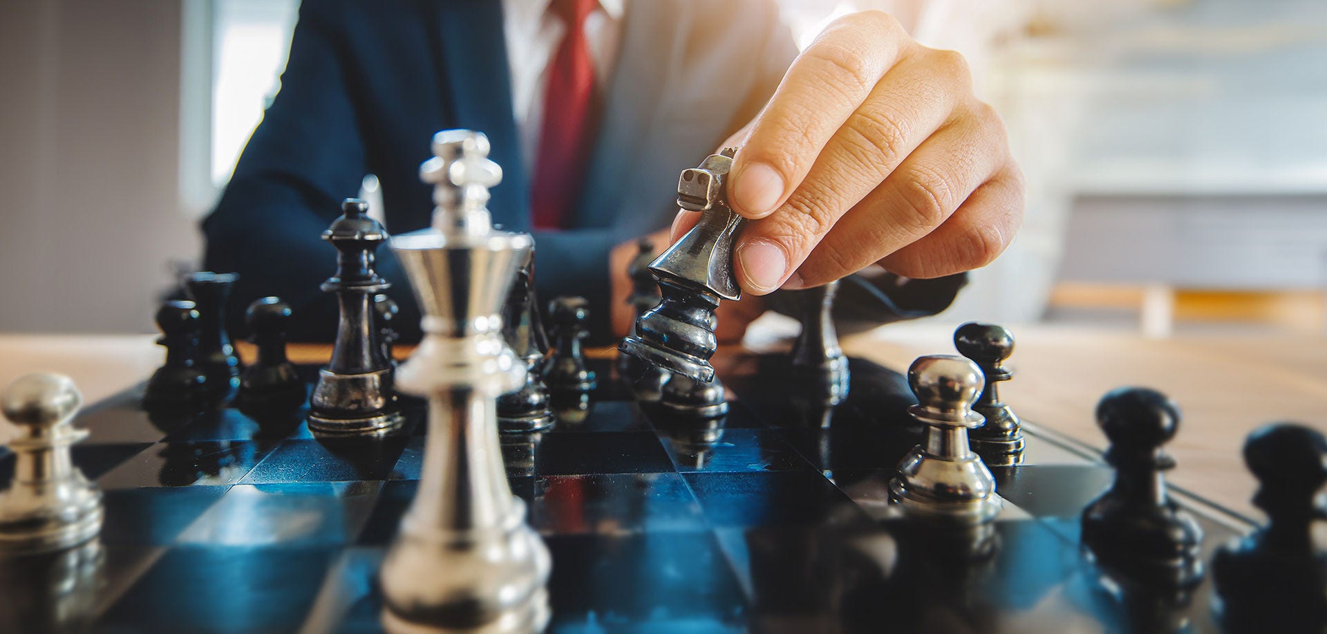 Forretningsmand, der flytter en skakbrik på et skakbræt – et koncept for idéer, konkurrence og strategi, forretningssucces, konkurrenceplanlægning, teamwork og strategisk tænkning