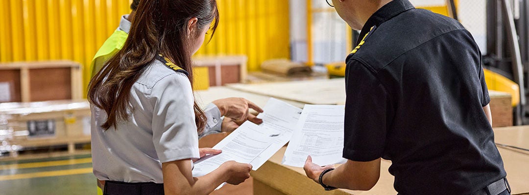 man and woman looking  at sheet of paper in a warehouse