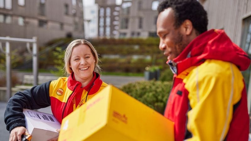 Two DHL Express employees having a chat outside a large building.