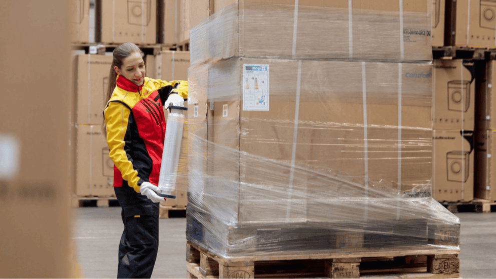 Addetta DHL Express che imballa un pallet