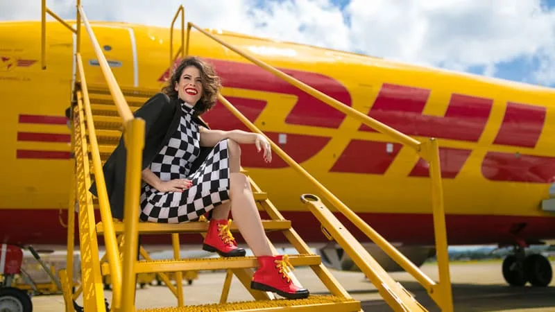 woman sitting in front of a DHL aeroplane