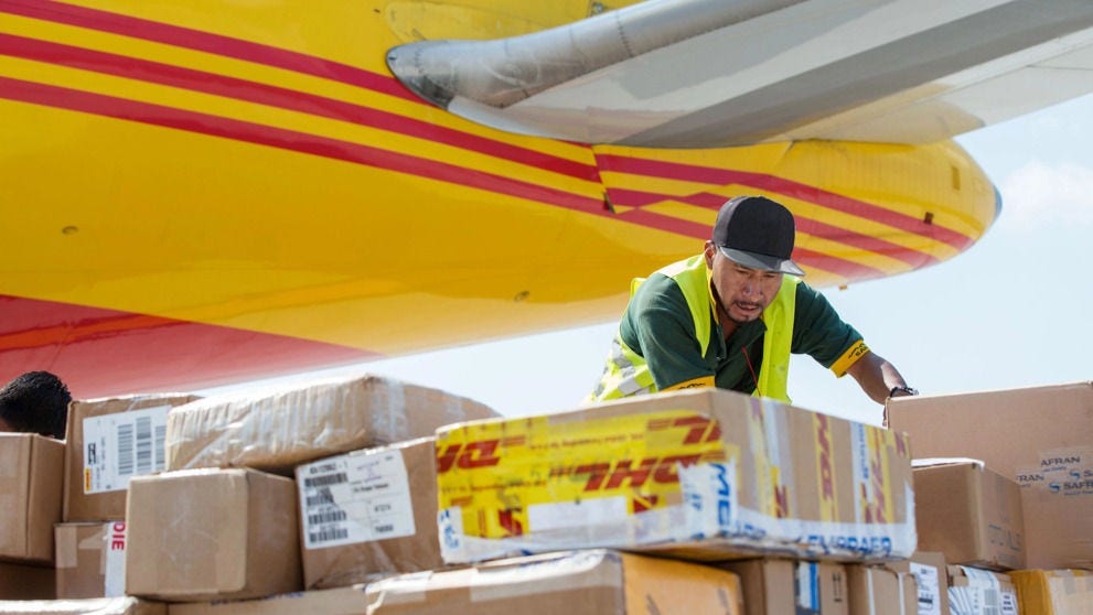 DHL工人在货机下方分拣待装机的跨境快件。
