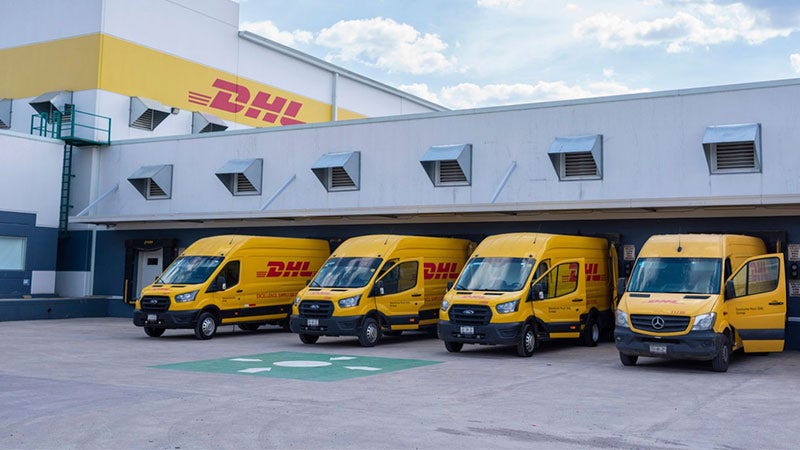 row of dhl vans parked at a facility in southeast asia