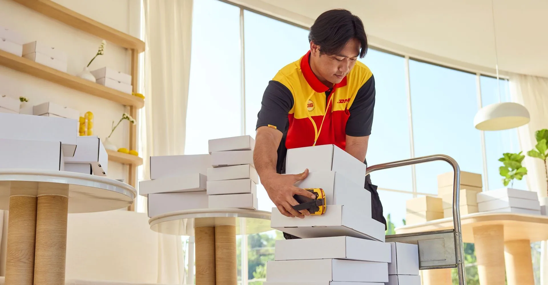 Seorang karyawan DHL memuat paket untuk diambil dengan gerobak tangannya.