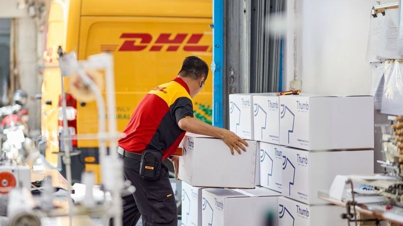 a dhl employee picking up boxes of textiles to export from india