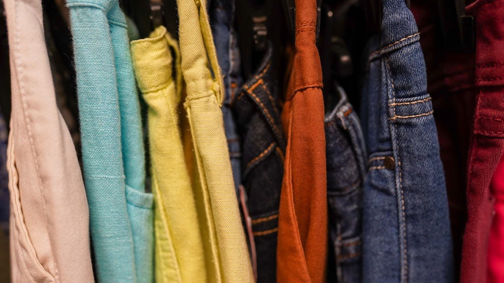 Clothes jeans on a hangers in the store second hand