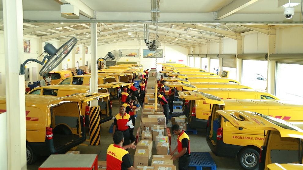 dhl express staff and vans in delivery hub