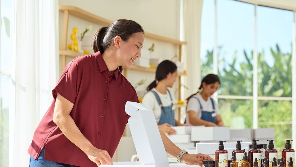female shop owner placing a thank-you card into a white parcel