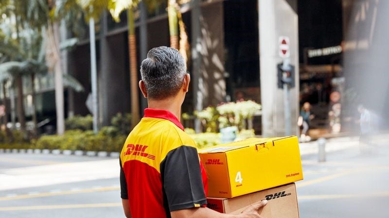 A DHL employee delivering two DHL parcels.