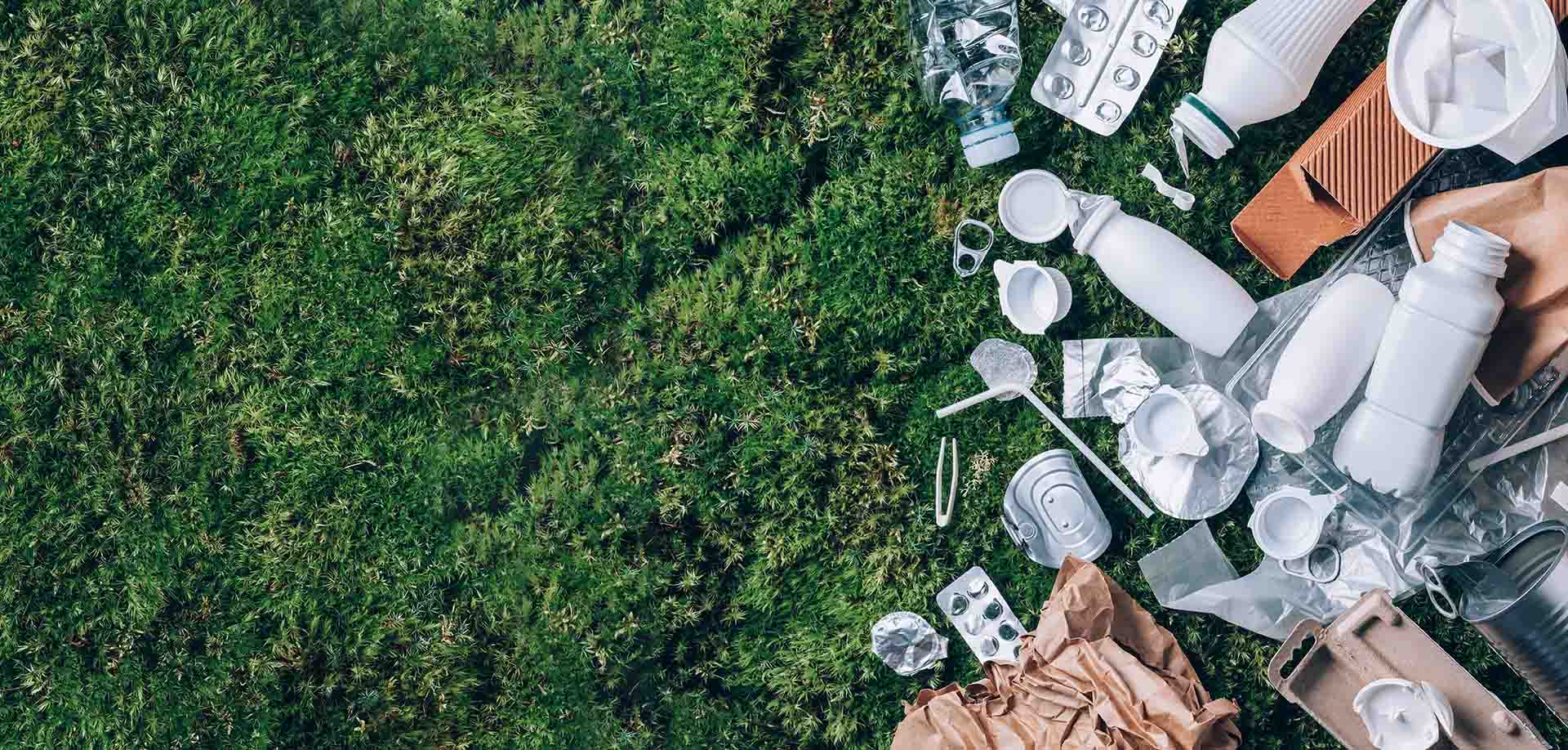 Food plastic packaging, trash on green moss background after picnic in forest.