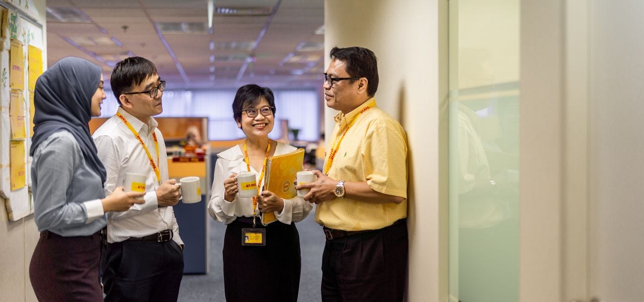 Four corporate workers have a casual discussion over a cup of coffee in the office