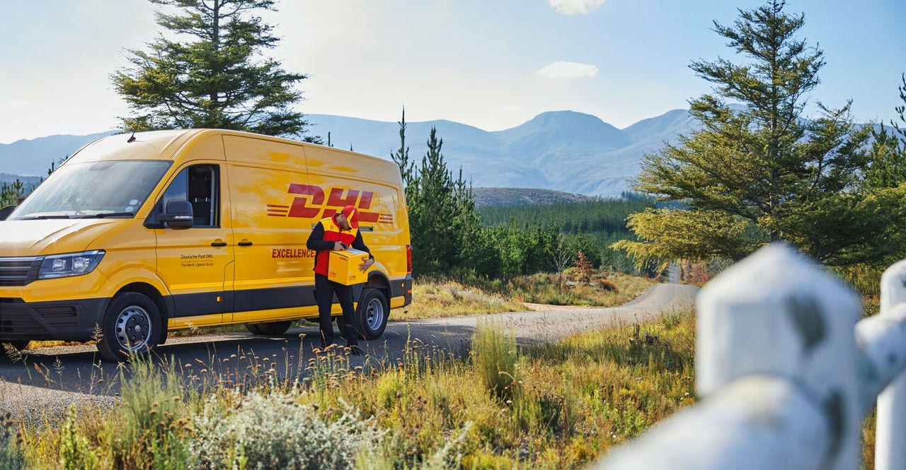 A DHL Express delivery van parked on a scenic rural road with a DHL courier holding a package
