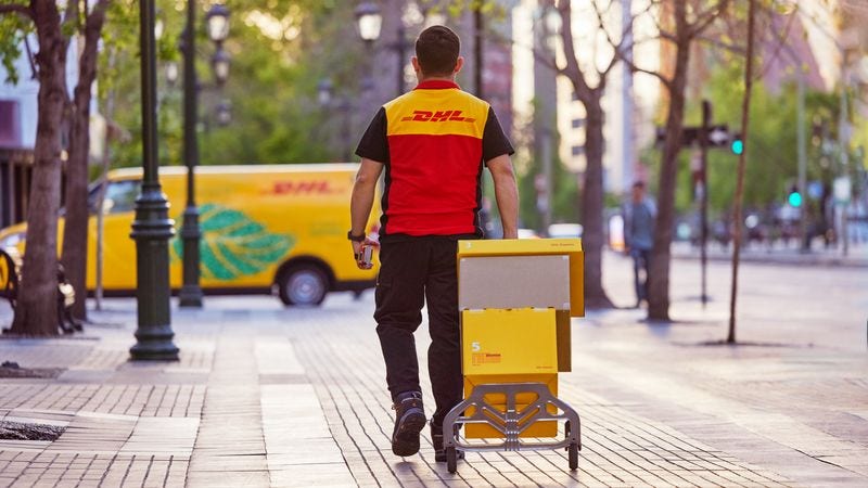 dhl express employee with a trolley delivering packages