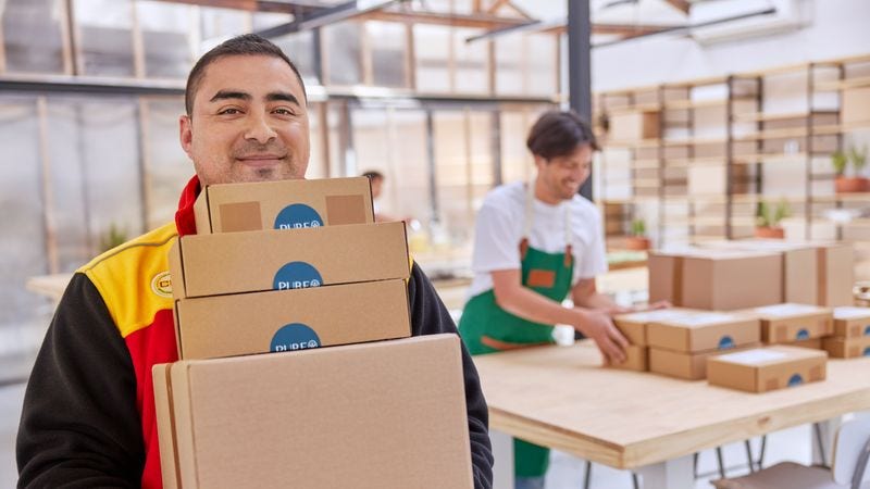dhl employee carrying parcels for overseas shipping using sustainable aviation fuel