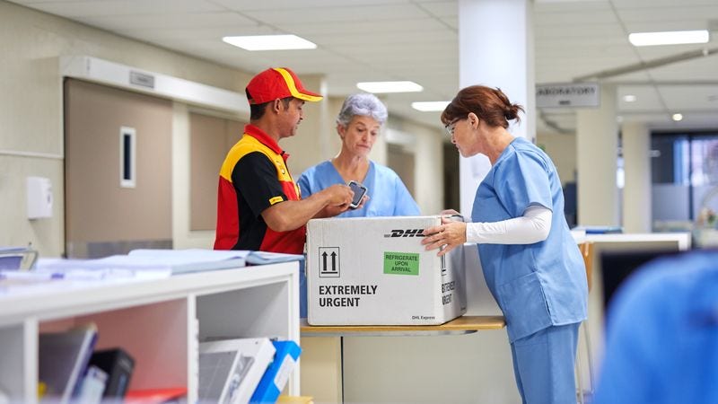 healthcare assistants passing the parcel to a dhl employee