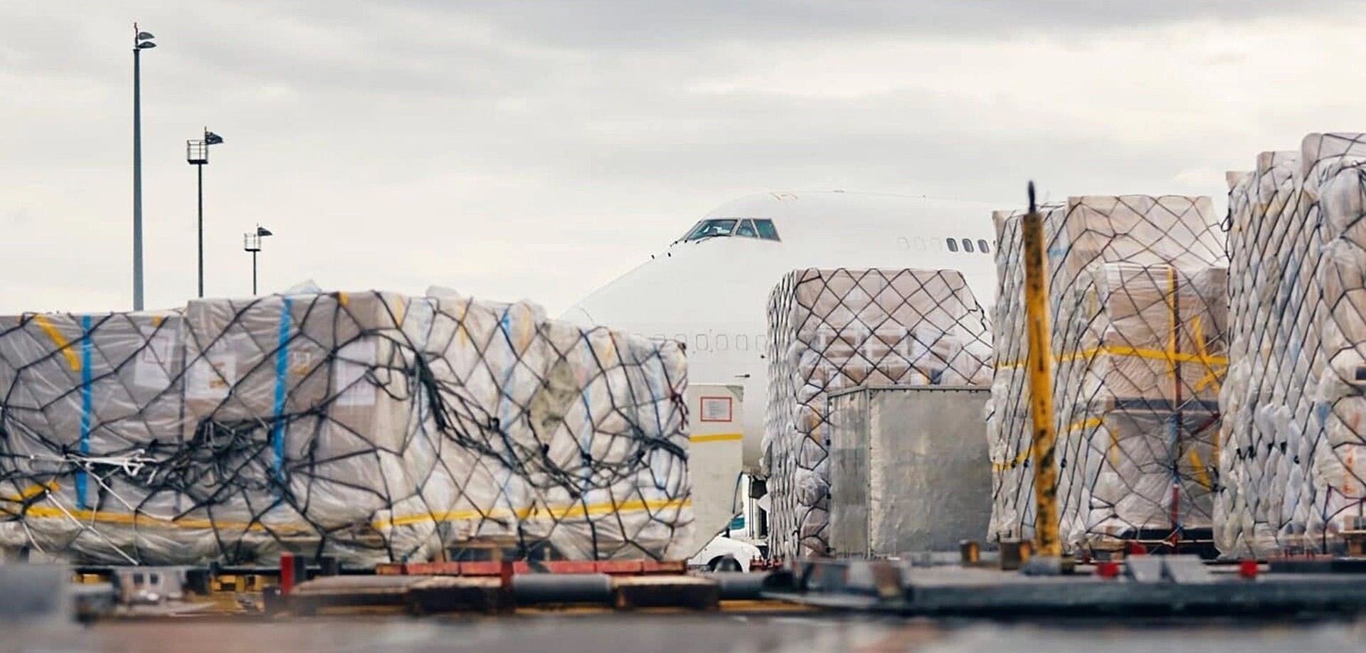 Paletes de carga embalados e presos com rede no pátio do aeroporto antes do embarque