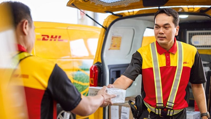 dhl express employee handing parcel to colleague