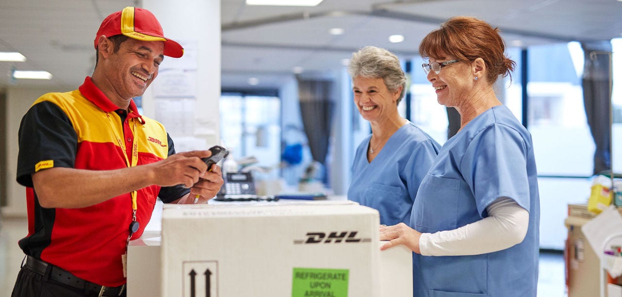 DHL courier scanning parcel with two medical professionals