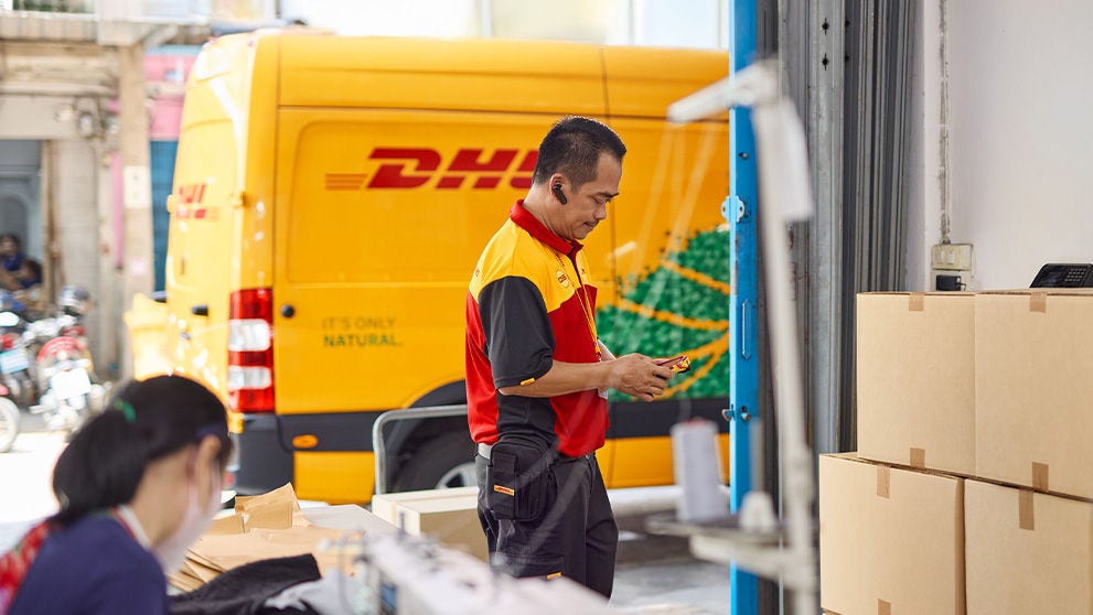 Un coursier DHL regarde un colis