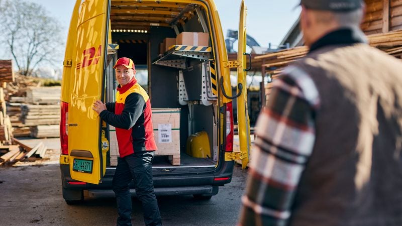 A male DHL employee transporting wood pallets for shipping to malaysia 