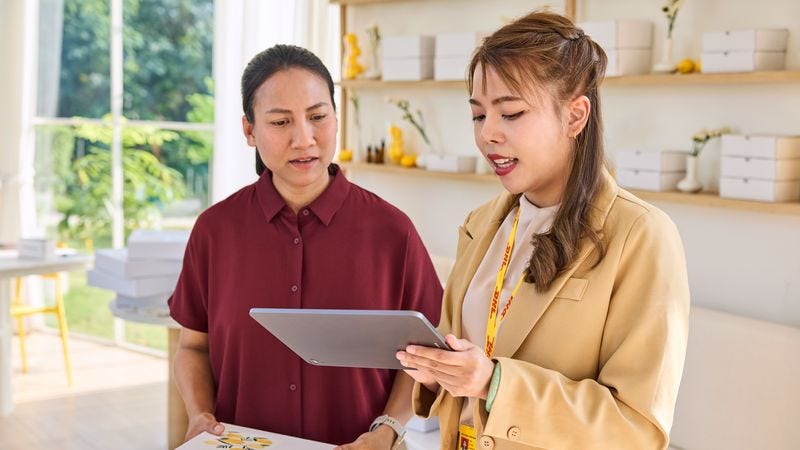 DHL Express employee explaining online tracking to a business owner in Indonesia