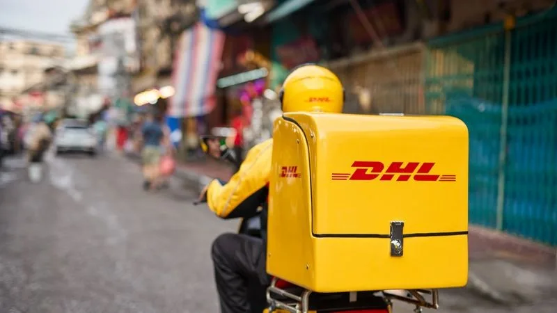 DHL rider driving through traffic to deliver package