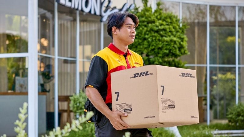 พนักงานชายของ DHL ที่เพิ่งรับพัสดุ DHL Express สีน้ําตาลที่ยั่งยืน