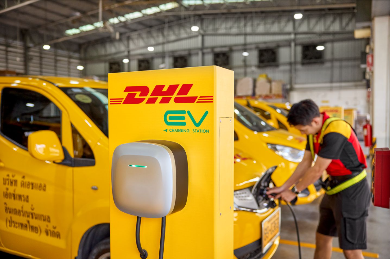 dhl employee charging an electric dhl van highlighting emerging sustainable logistics trends