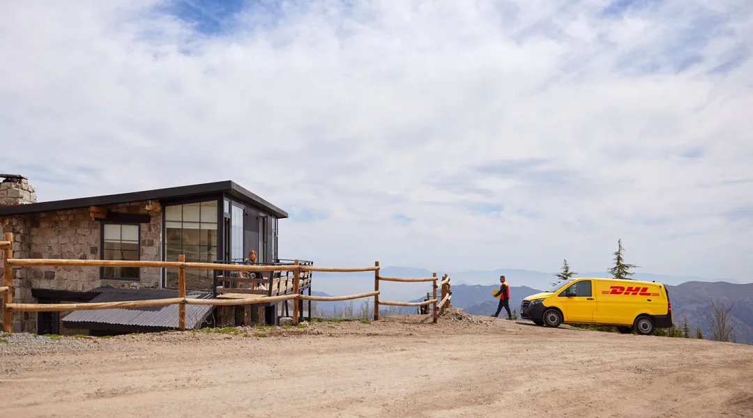 A DHL courier deiverying a package in a rural landscape