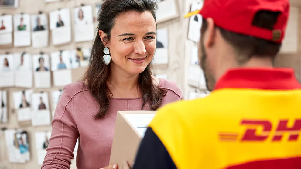 woman in pink blouse smiling at DHL courier