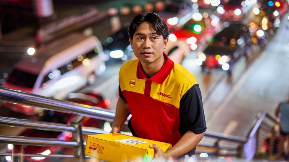 DHL Express employee holding onto a parcel, background is blurred.