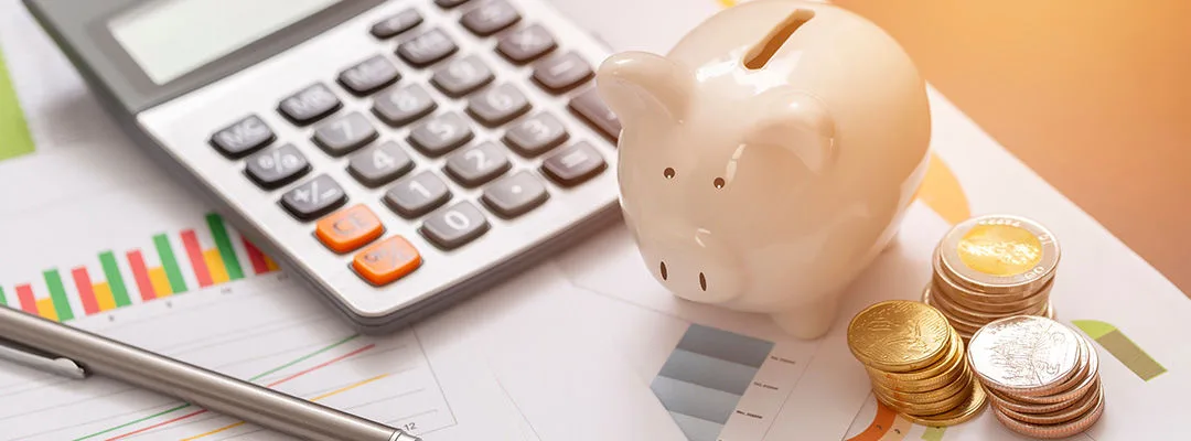 piggy bank with coins and a calculator on a table
