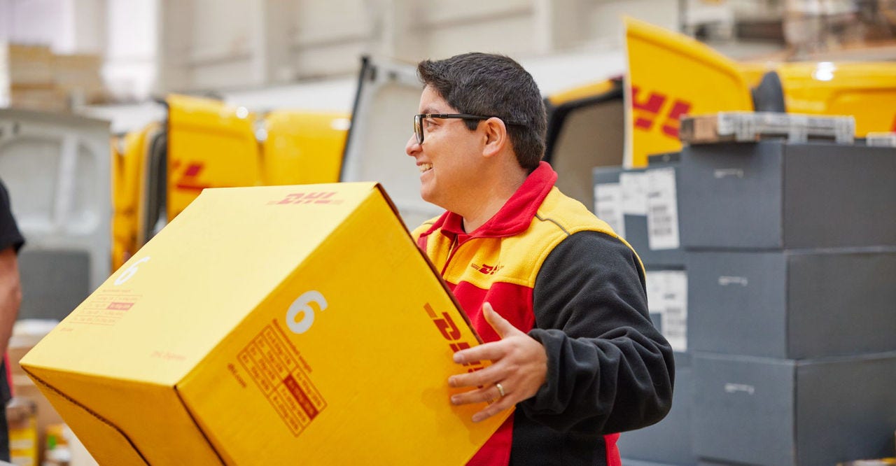 A DHL employee handling a large parcel.