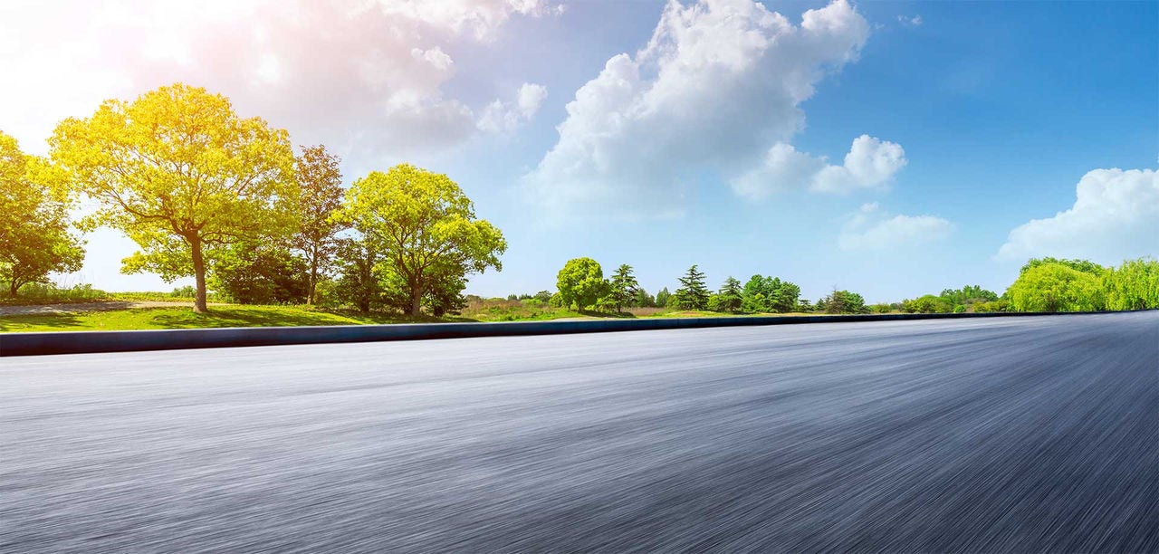 Fast moving asphalt road and green forest landscape.
