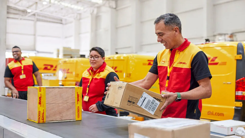 שלושה موظفين من DHL يحملون الطرود
