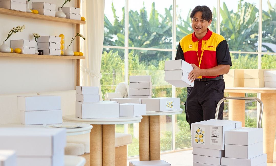 A male DHL Express employee loads parcels onto a handcart.