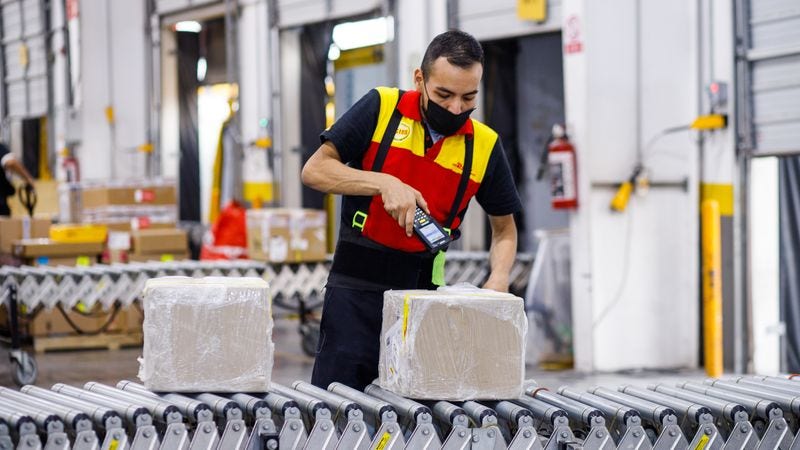 Karyawan DHL Express menggunakan pemindai pintar untuk mengelola pengiriman di pusat distribusi logistik