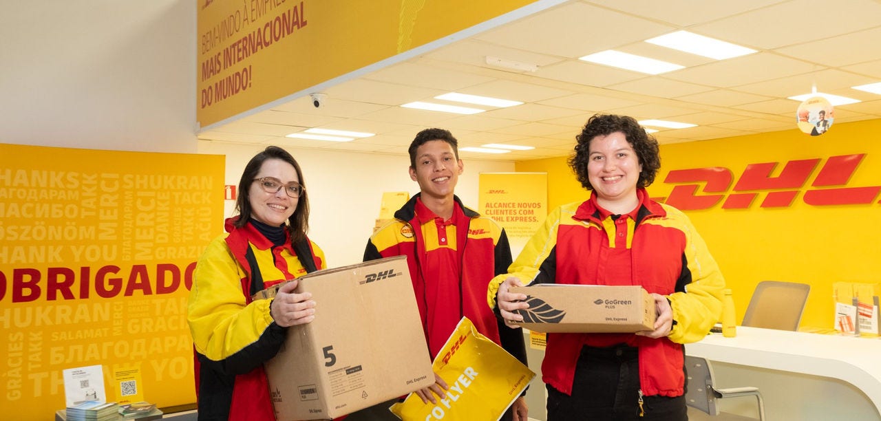DHL Store team holding boxes and a DHL envelope at the store counter