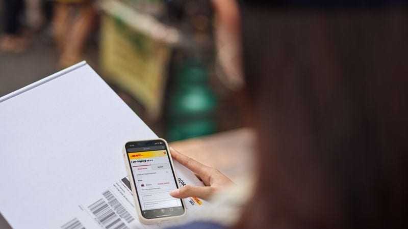a female business owner holding her smartphone with a white parcel below it