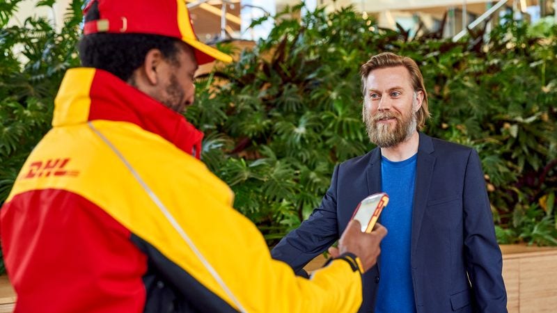 dhl employee handing scanner to a customer for his signature