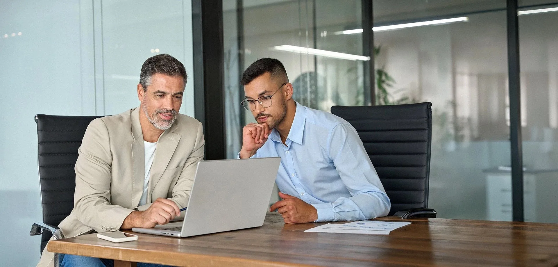 Two professionals reviewing the terms of a trade agreement on a laptop