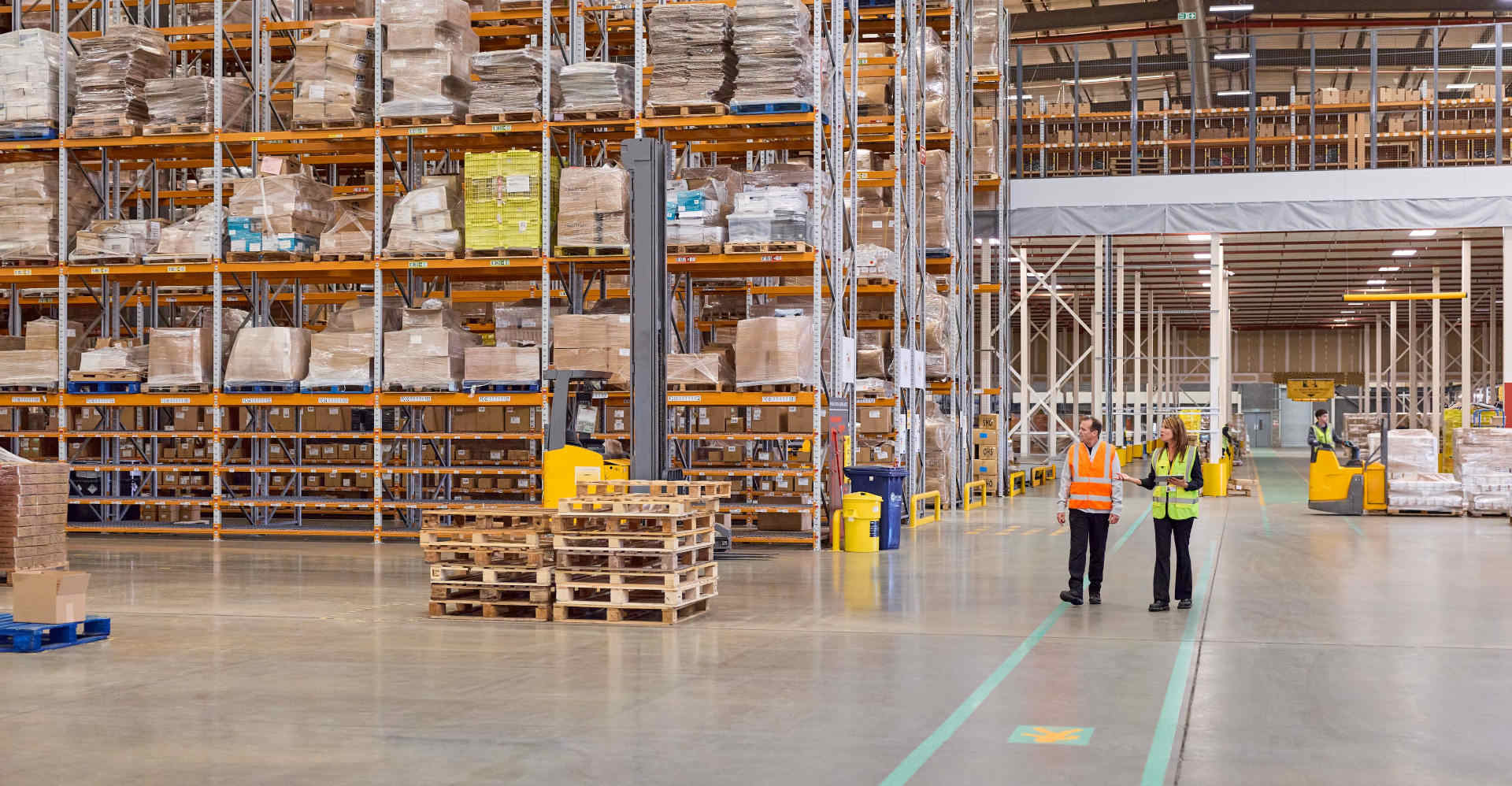 A female DHL expert and a male business customer are inspecting a warehouse.