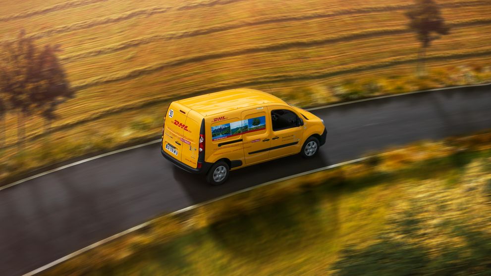 DHL Express van driving on road bordered by farmland
