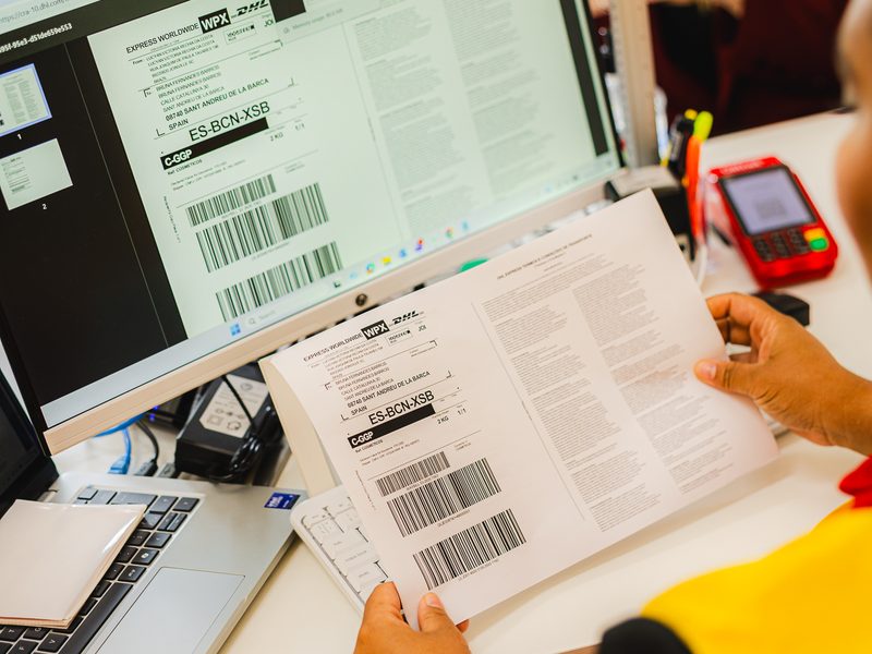 Atendente da Loja DHL com a documentação e a etiqueta do envio